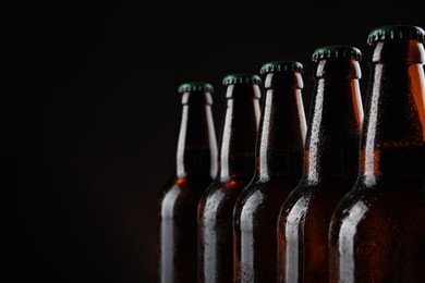 Photo of Many bottles of beer on dark background, closeup. Space for text