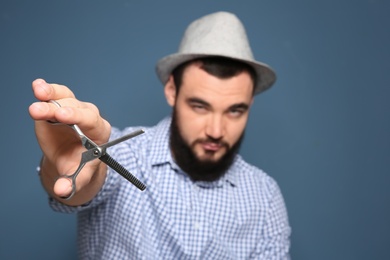 Photo of Professional hairdresser with scissors on color background