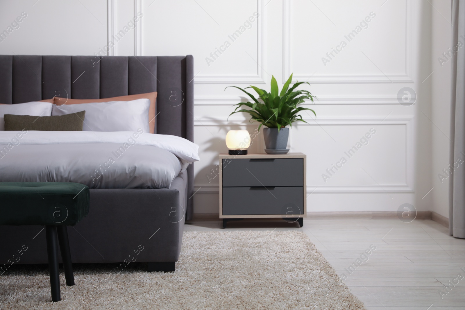 Photo of Stylish bedroom interior with large comfortable bed and ottoman