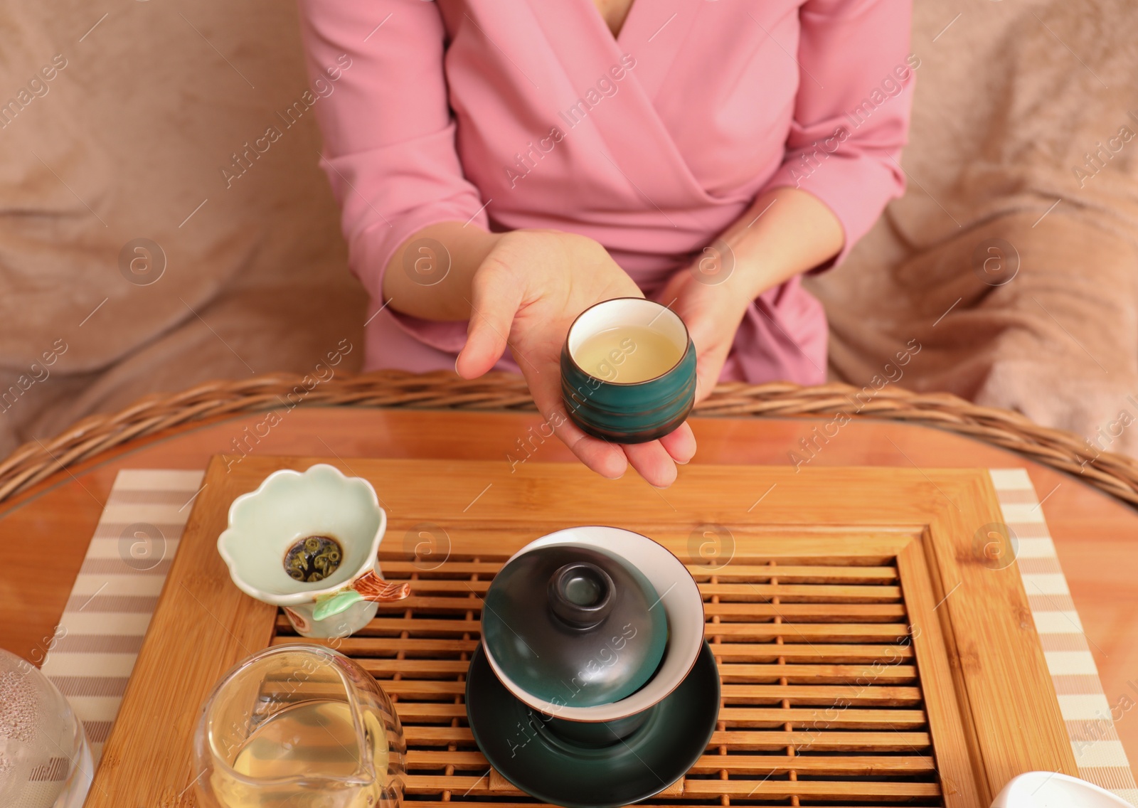 Photo of Master offering cup of freshly brewed tea during traditional ceremony at table, closeup