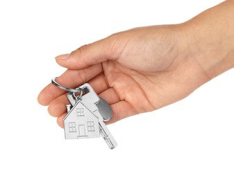 Photo of Woman holding key with metallic keychain in shape of house on white background, closeup