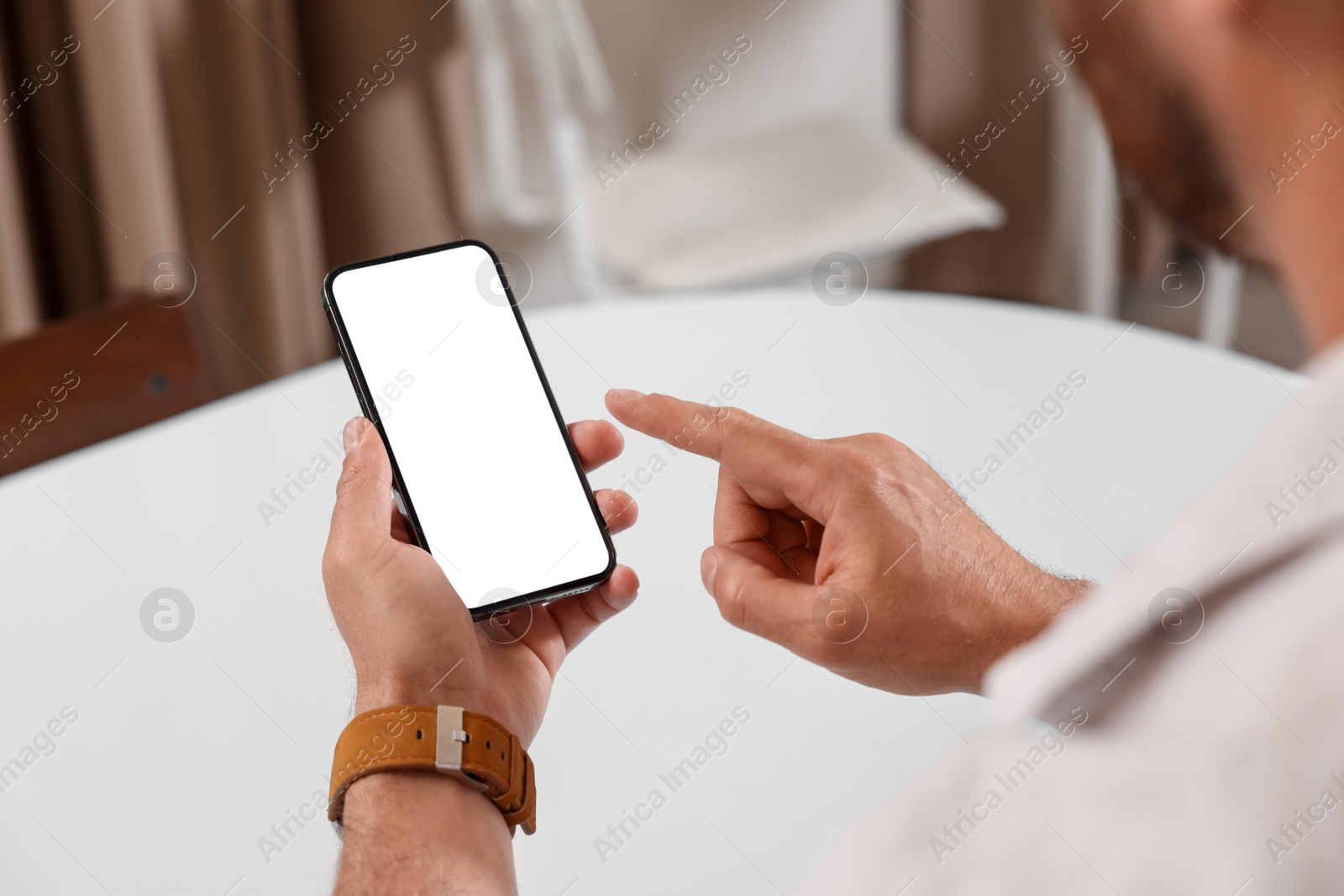 Photo of Man using mobile phone at table indoors, closeup