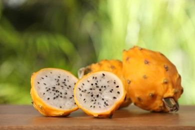 Delicious cut and whole dragon fruits (pitahaya) on wooden table