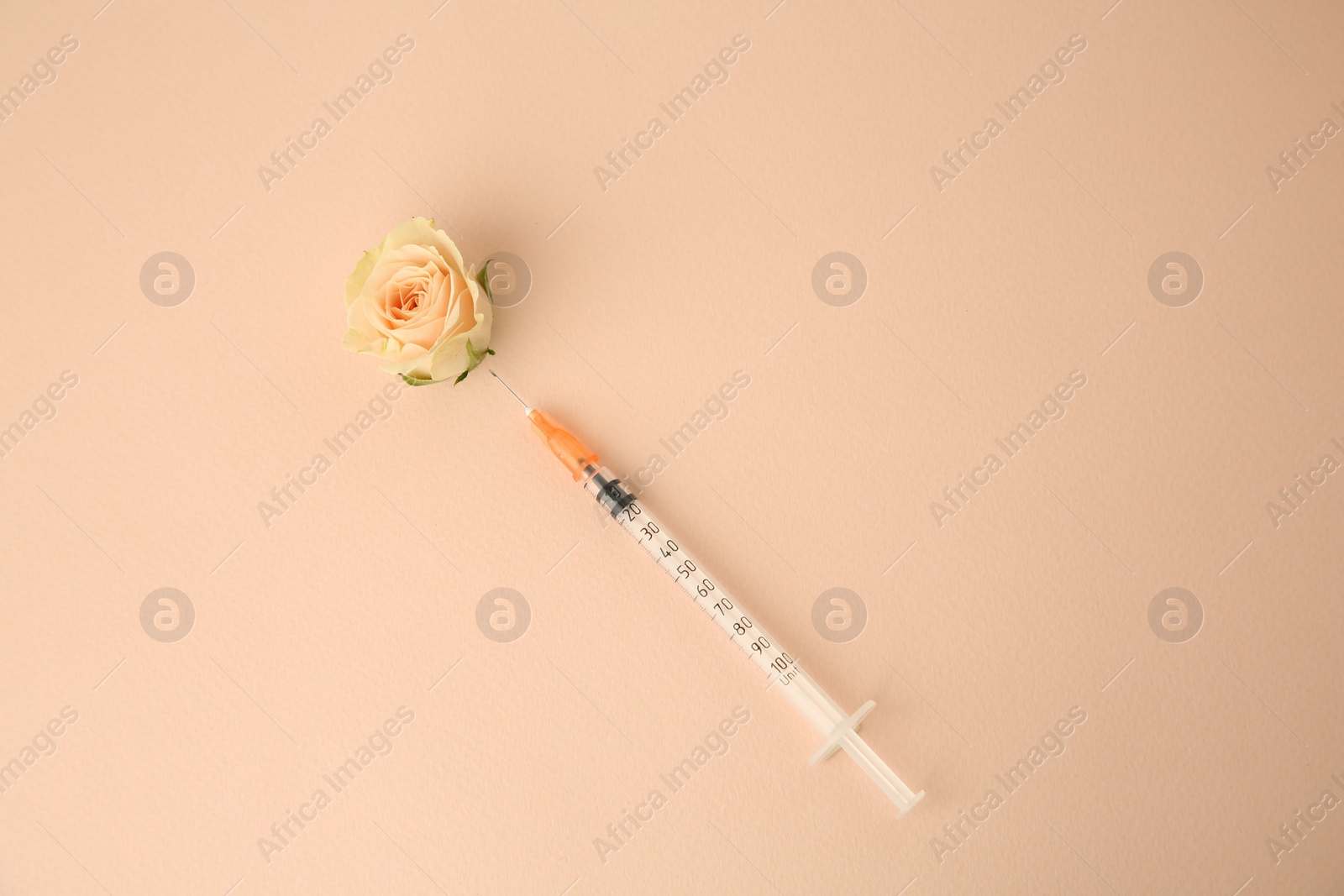 Photo of Medical syringe and beautiful rose on beige background, top view