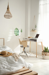 Photo of Stylish room interior with workplace and bed