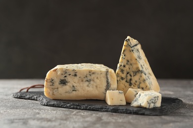 Slate board with delicious blue cheese on stone surface