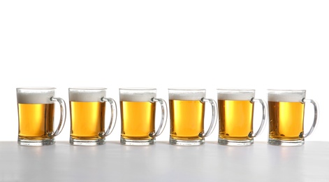 Photo of Row of full beer mugs on white background