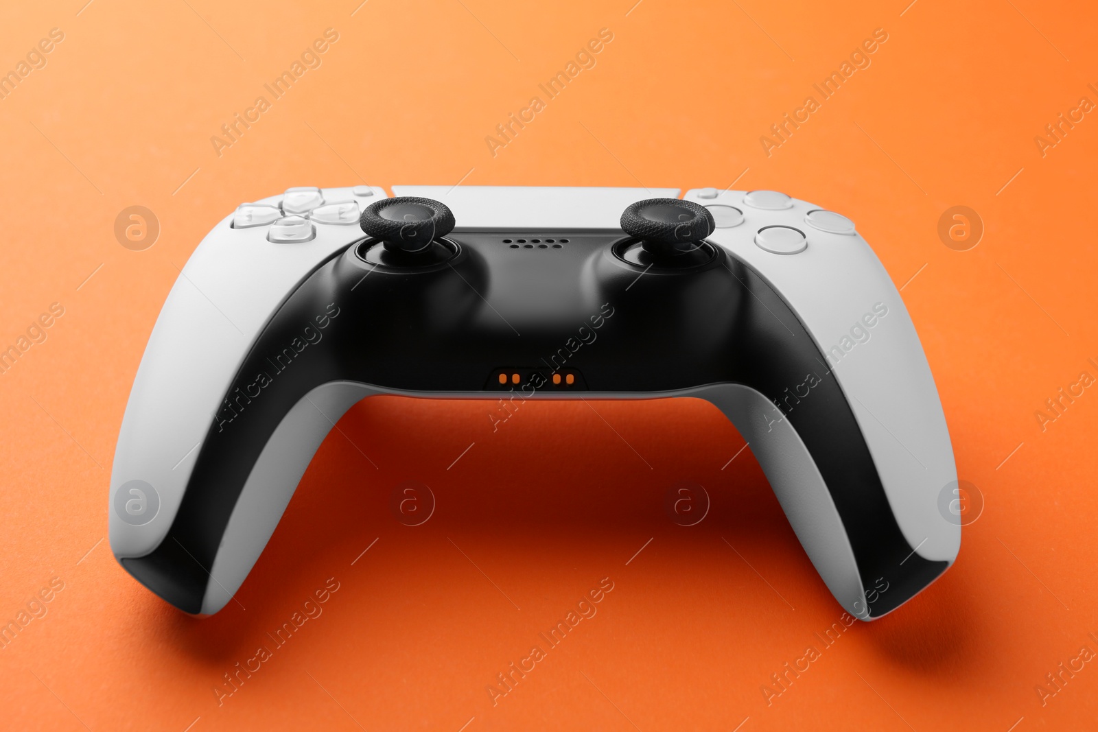 Photo of One wireless game controller on orange background