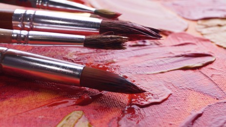 Many brushes on artist's palette with mixed paints, closeup