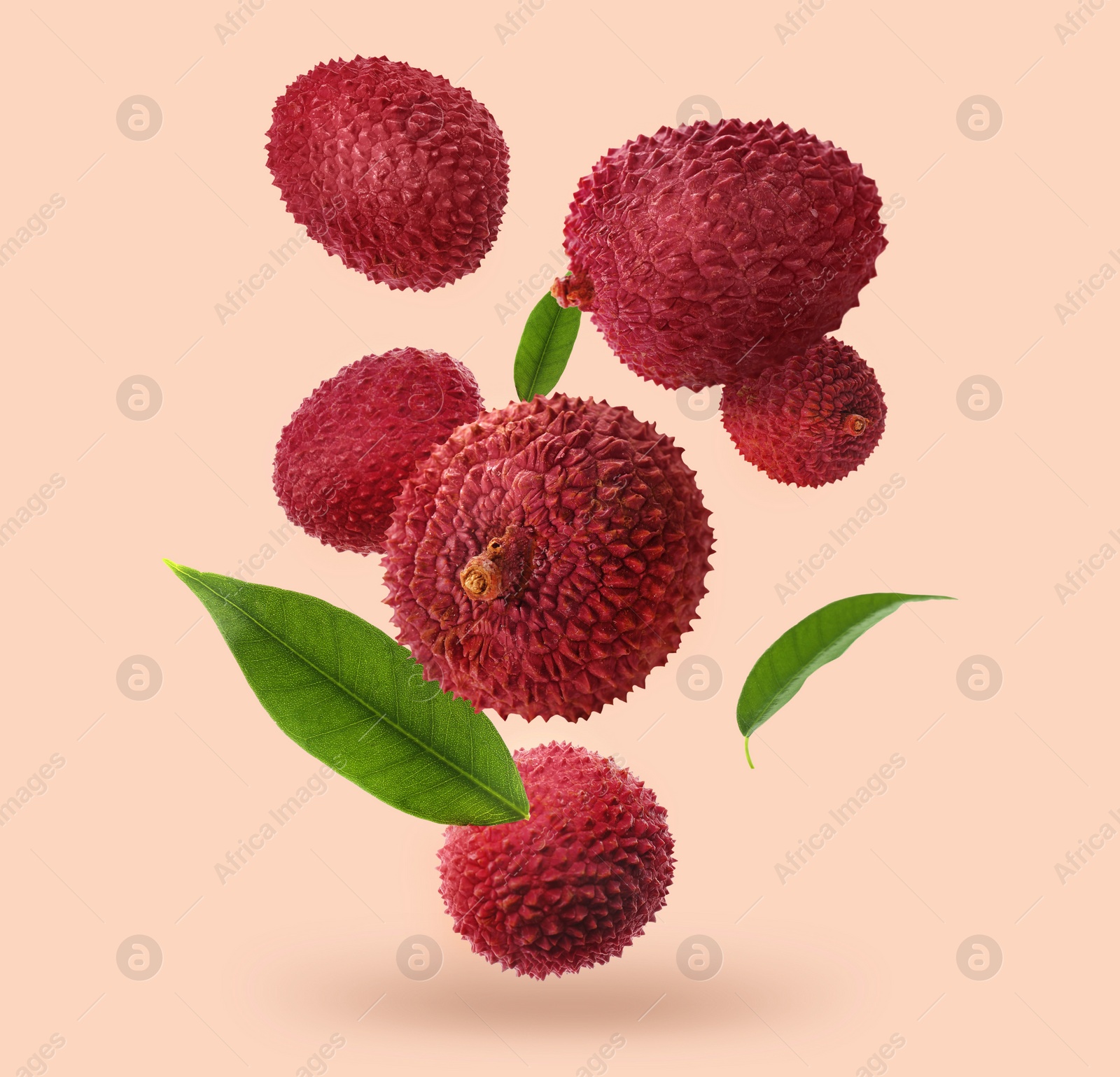 Image of Fresh lychees with green leaves falling on beige background