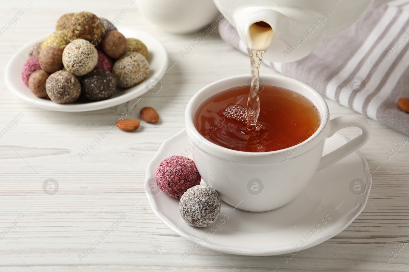 Photo of Pouring tea into cup on white wooden table