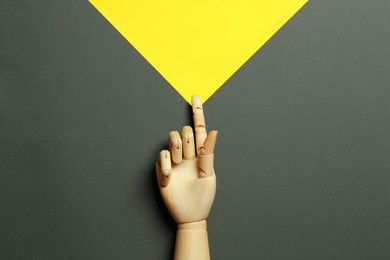 Wooden mannequin hand on color background, top view