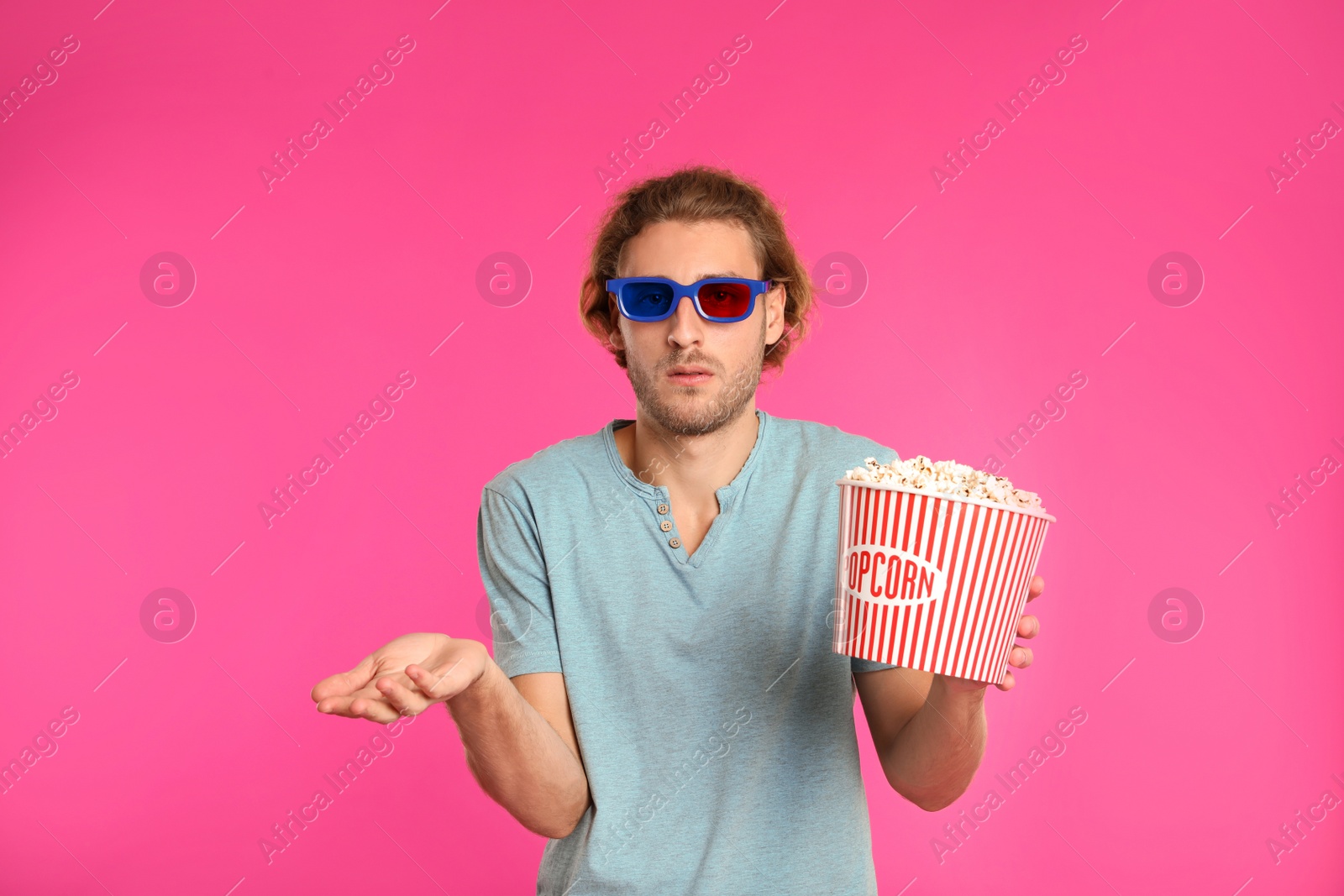 Photo of Emotional man with 3D glasses and popcorn during cinema show on color background