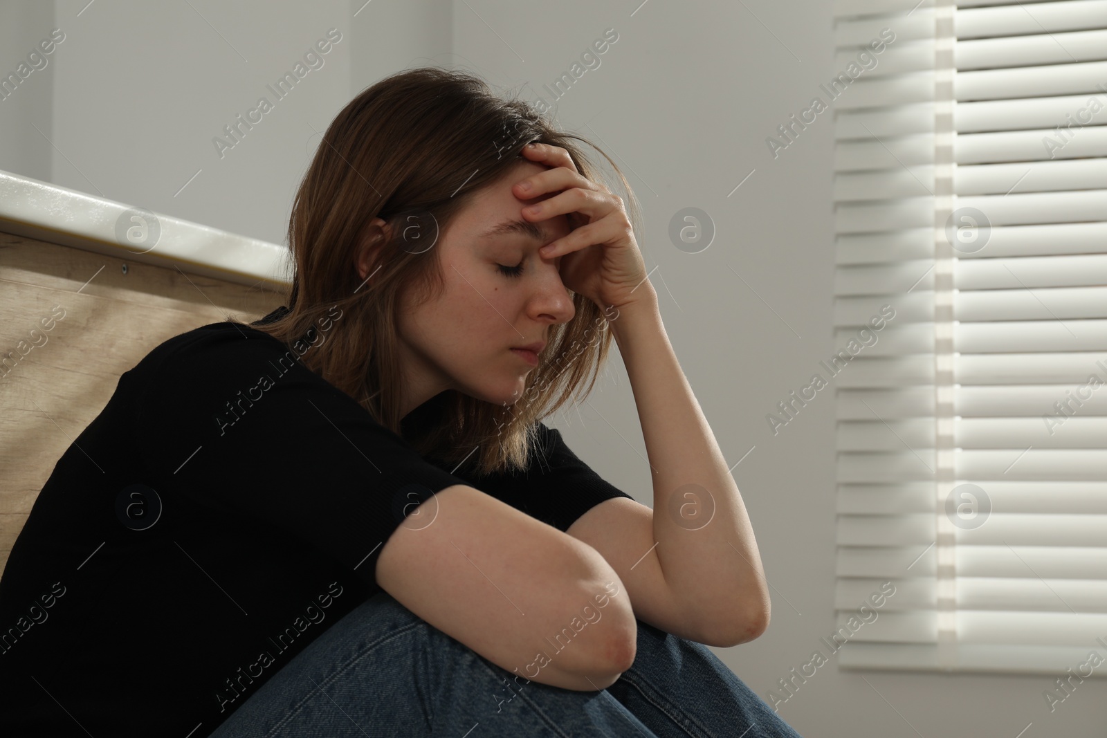 Photo of Sad young woman sitting on indoors, space for text