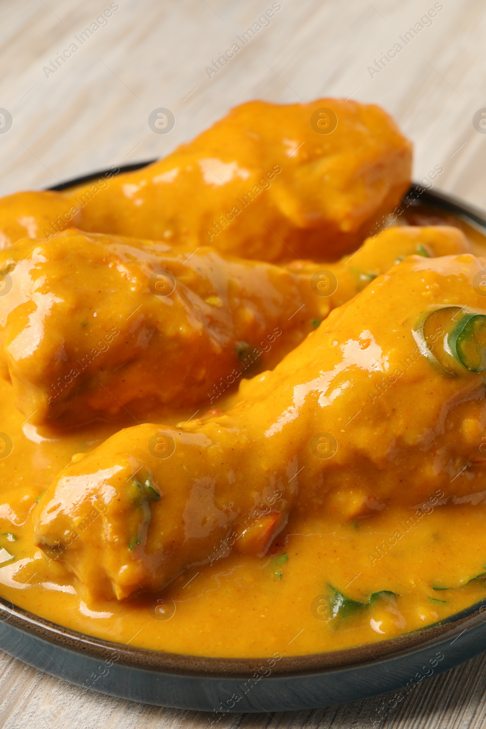 Photo of Tasty chicken curry on wooden table, closeup