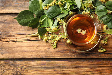 Photo of Cup of tea and linden blossom on wooden table, flat lay