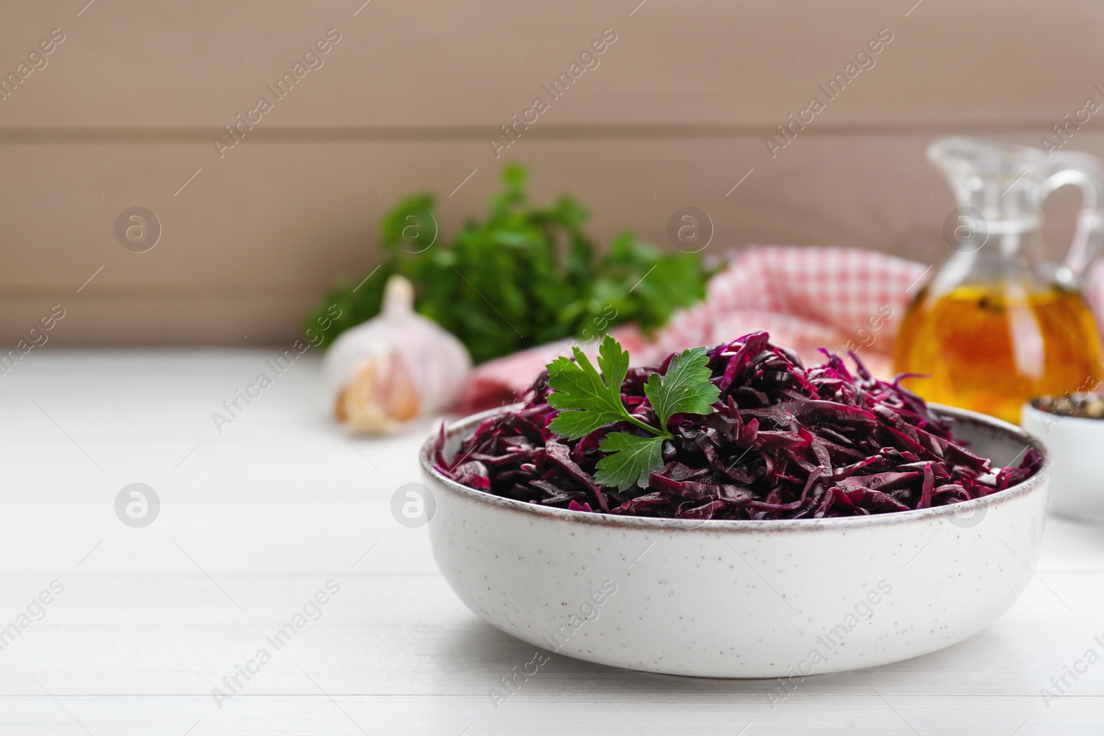 Photo of Tasty red cabbage sauerkraut with parsley on white wooden table. Space for text