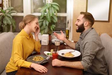 Lovely young couple having pasta carbonara for dinner at restaurant