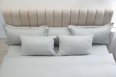 Photo of Many soft pillows and blanket on large comfortable bed indoors