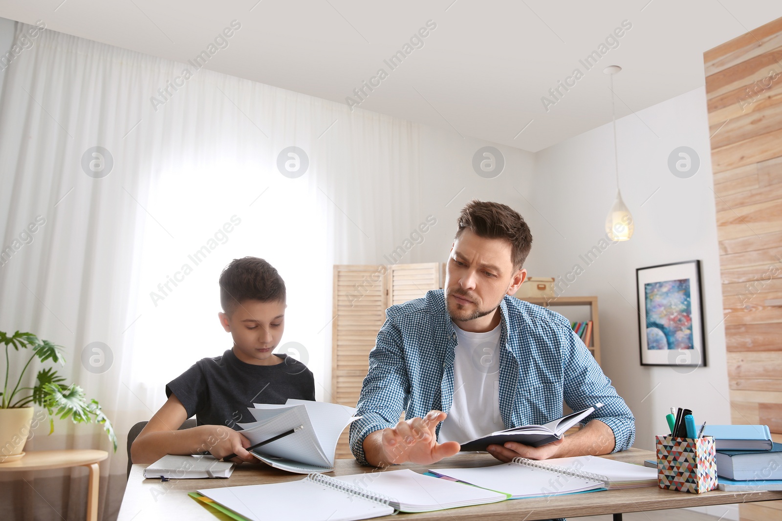 Photo of Dad helping his son with homework in room