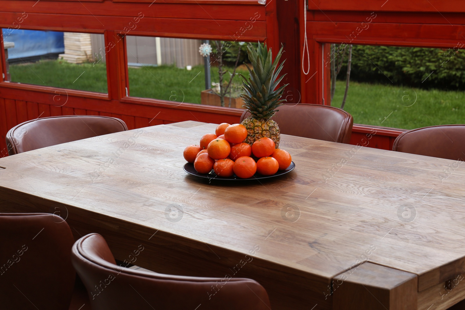 Photo of Wooden table with fruits and stylish chairs on terrace