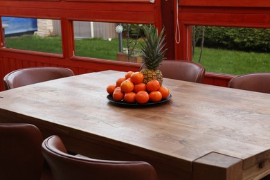 Photo of Wooden table with fruits and stylish chairs on terrace