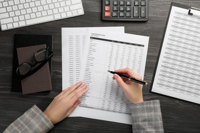 Photo of Woman working with accounting documents at wooden table, top view
