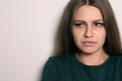 Photo of Abused young woman on light background, space for text. Stop violence