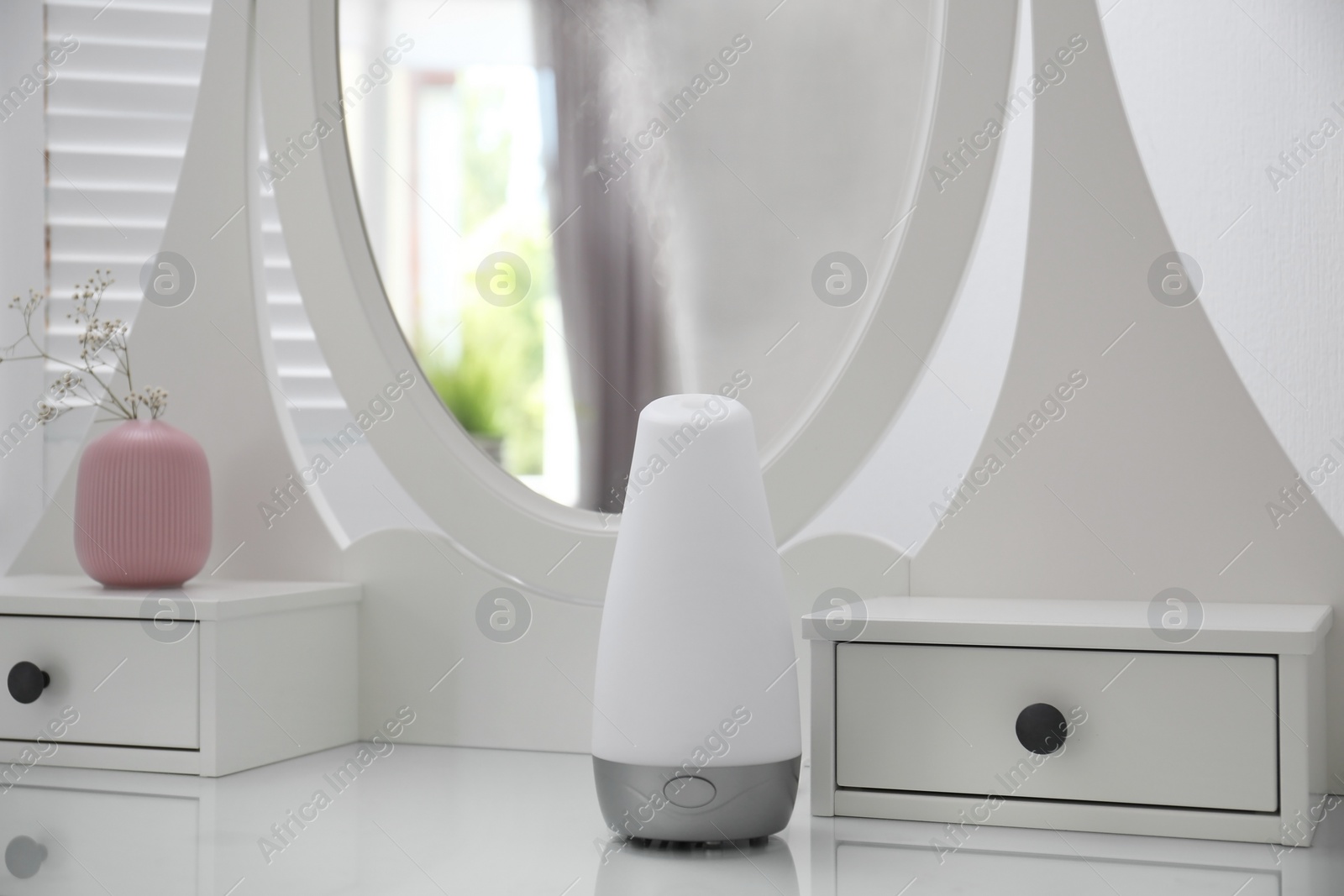 Photo of Essential oils diffuser on white table   in room. Space for text