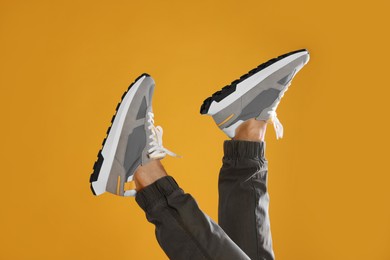 Man wearing stylish sneakers on yellow background, closeup