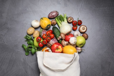 Photo of Bag with fresh vegetables and apples on dark background, flat lay