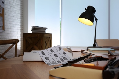 Photo of Detective workplace with vintage typewriter and fingerprints in office