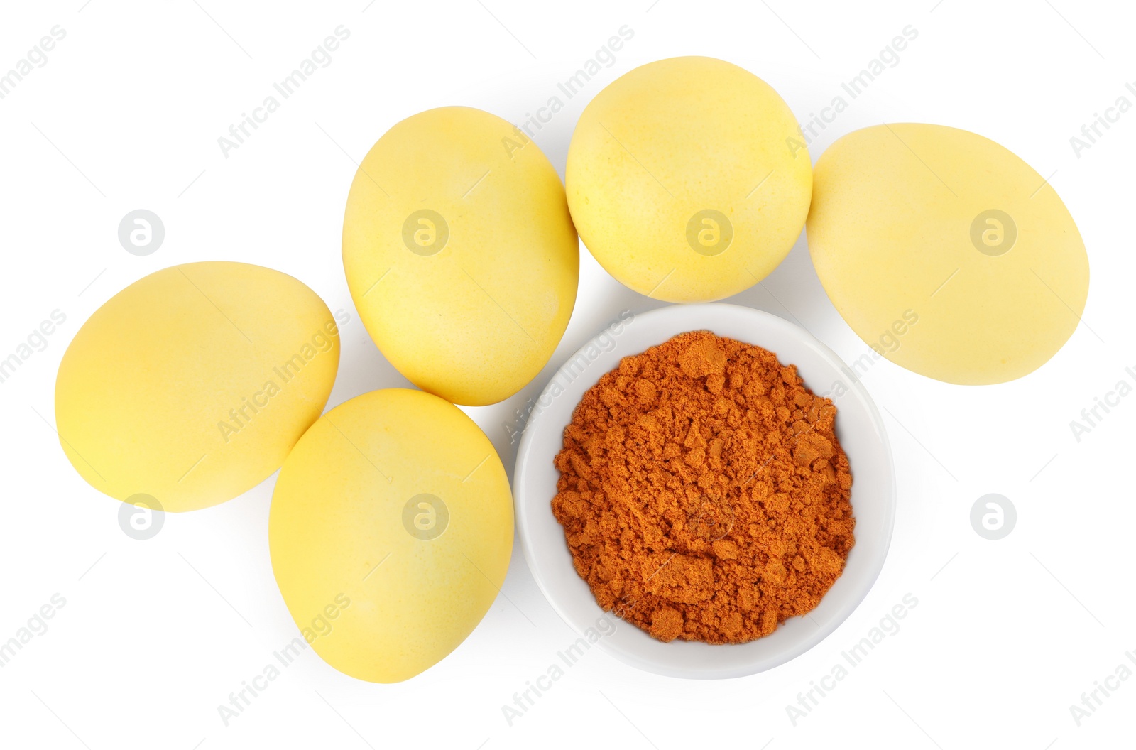 Photo of Yellow Easter eggs painted with natural dye and turmeric powder in bowl on white background, top view