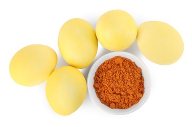 Photo of Yellow Easter eggs painted with natural dye and turmeric powder in bowl on white background, top view