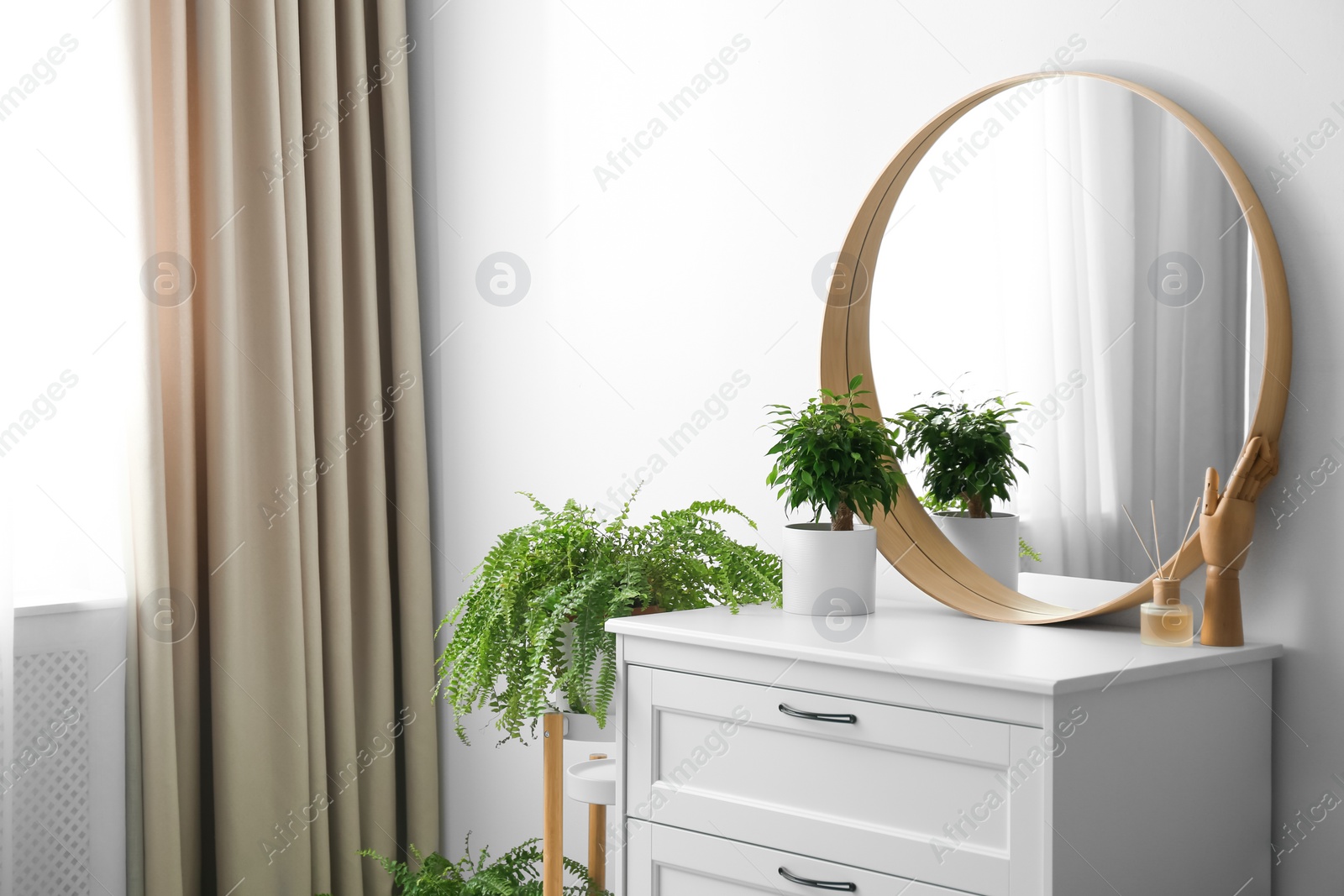 Photo of Round mirror and chest of drawers near white wall in room. Modern interior design