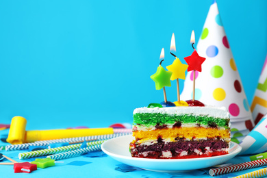 Piece of cake with candles and birthday decor on light blue background, space for text