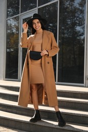 Photo of Beautiful young woman with stylish waist bag on city street