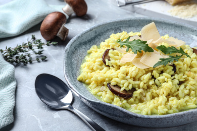 Delicious risotto with cheese and mushrooms on grey marble table, closeup