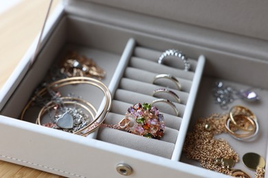 Photo of Jewelry box with many different accessories on wooden table, closeup