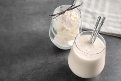 Photo of Glasses with milk shake and tasty vanilla ice cream on grey background