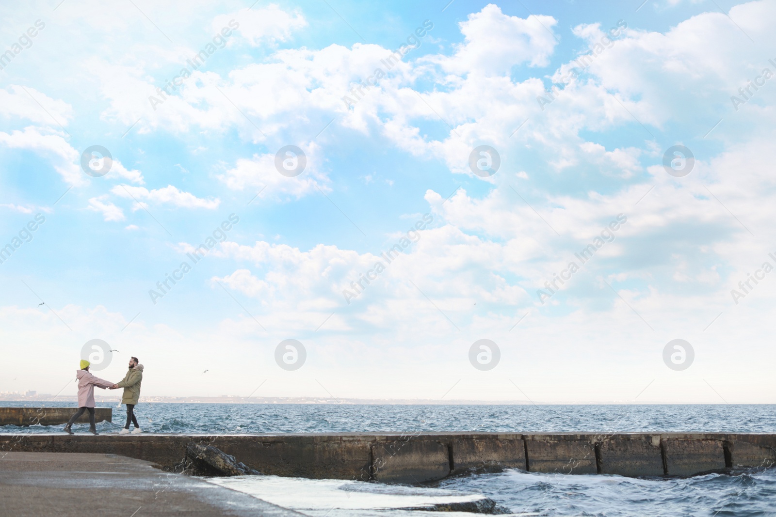 Photo of Lovely young couple walking on pier near sea