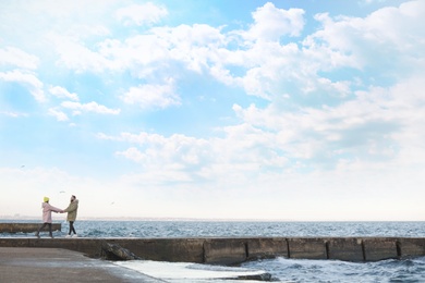 Photo of Lovely young couple walking on pier near sea