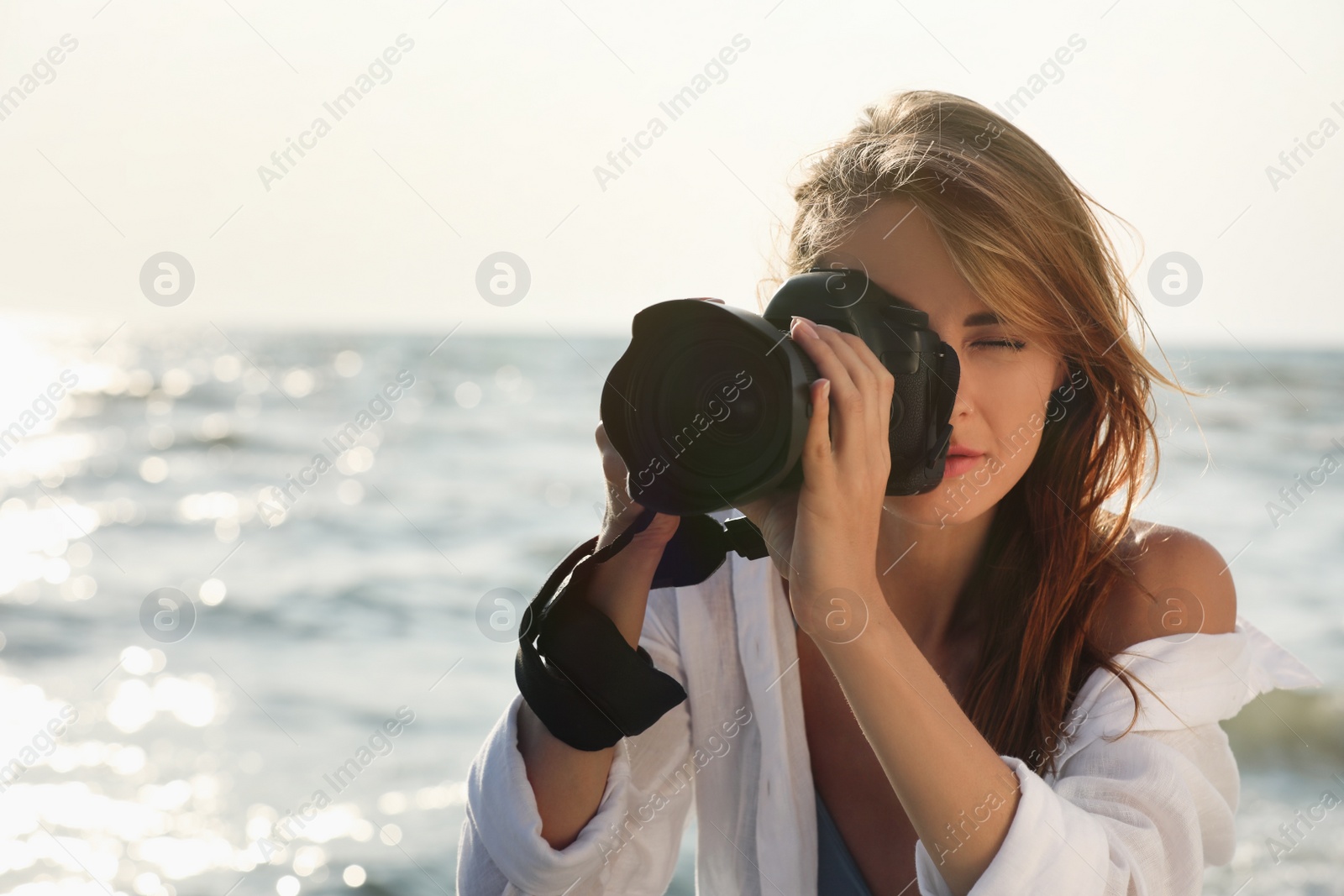 Photo of Photographer taking photo with professional camera near sea