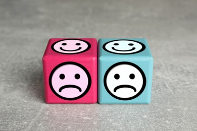 Image of Complaint. Pink and light blue wooden cubes with sad and happy on different sides