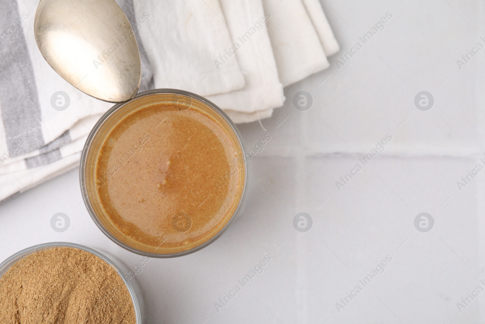 Photo of Soluble fiber with water in glass, powder and spoon on white tiled table, top view. Space for text