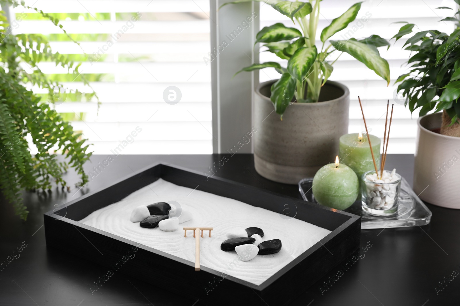 Photo of Beautiful miniature zen garden, candles and incense sticks on black table indoors