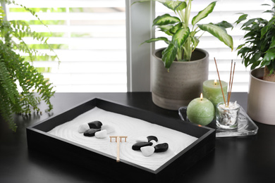 Beautiful miniature zen garden, candles and incense sticks on black table indoors