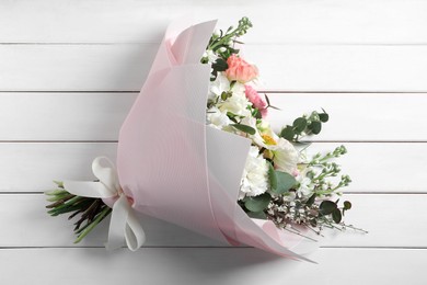 Photo of Bouquet of beautiful flowers on white wooden table, top view