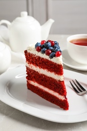 Photo of Plate with piece of delicious homemade red velvet cake on table