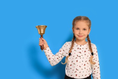 Photo of Pupil with school bell on light blue background